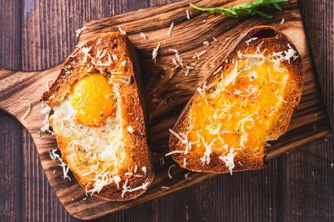 Close up of bread baked with egg and cheese on a cutting board top view Stock Photos