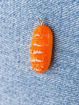 Close-up of a bread roll-shaped pendant for jewelry making, displayed on a bl Stock Photos