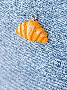 Close-up of a bread roll-shaped pendant for jewelry making, displayed on a bl Stock Photos