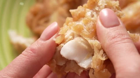 Close-up of a breaded fish fillet being pulled apart by hand. Stock Footage 260344776