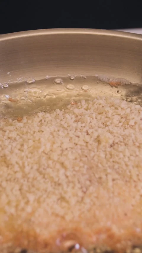 Close-up of breaded pork cutlet frying in hot oil in a stainless steel pan in a Stock Footage 329266063
