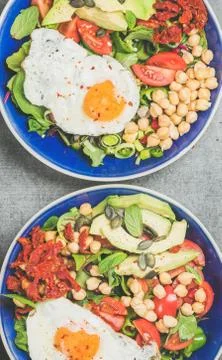 Close-up of breakfast with fried egg, chickpea, vegetables, seeds, greens Stock Photos