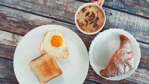 Close-up of breakfast with fried egg, toast, croissant, and coffee indoors Stock Footage 340879897