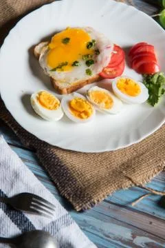 Close up of breakfast ingredients fried egg with bacon and pieces of boiled eggs Stock Photos