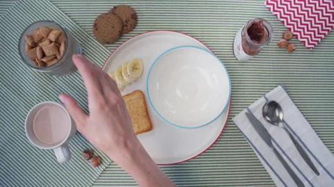 Close up breakfast preparation, women's hands pour cereal into plate and pour Stock Footage 138055317