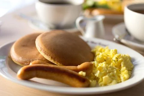 Close up breakfast with sausages, bread, scrambled eggs and pancakes Stock Photos