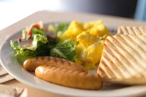 Close up breakfast with sausages, bread, scrambled eggs and vegetables salad Stock Photos