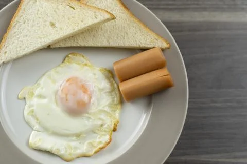 Close-up of breakfast on a white plate in the left corner of the wooden floor Stock Photos