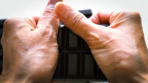 Close-up of breaking a chocolate bar into two pieces by hand Stock Footage 277497469