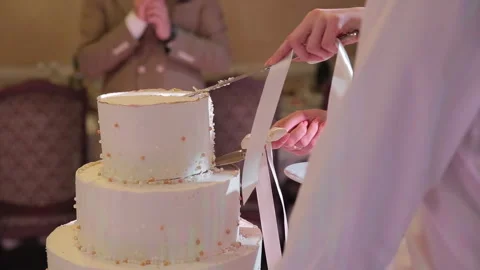 A close-up of the bride and grooms hands cutting the wedding cake, with a Stock Footage 322020561