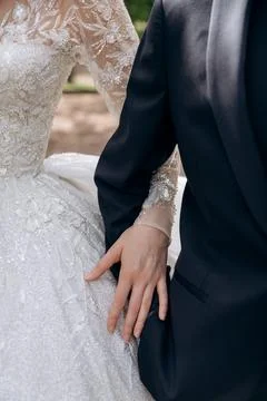 Close up of a bride hand resting gently on the groom arm wearing a dark blue Stock Photos