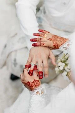 Close-up of a bride with henna-patterned hands placing a diamond ring Stock Photos