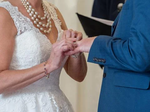 Close up of a bride placing the wedding ring onto her husbands hand. Stock Photos