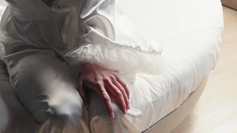 Close-up of Bride in Satin Robe Sitting on Bed in Soft Morning Light Stock Footage 336422611