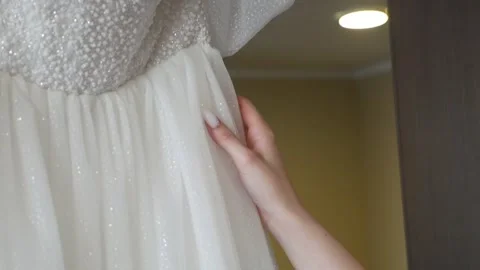 Close-up of the bride tenderly touching her pearl wedding dress, Stock Footage 334120250