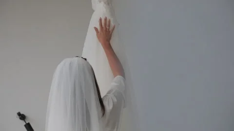 Close-up of a bride in a vail touching gently a white satin wedding dress Stock Footage 321647232