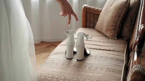Close-up of the bride's hand, which comes to the sofa and picks up wedding shoes Stock Footage 200524268