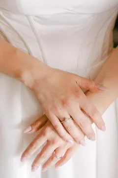 Close-up of a brides hands elegantly resting on her wedding dress, showcasing Stock Photos