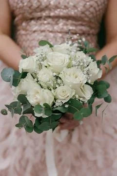 Close-up of a bride's hands holding an elegant wedding bouquet featuring fresh Stock Photos