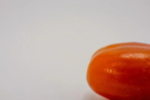 Close-up of a bright orange fruit, possibly a tomato, against a plain white b Stock Photos