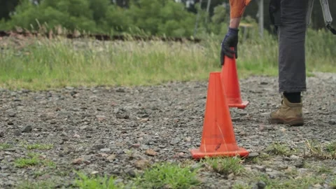Close-up of bright orange safety cones placed on a gravel pathway to mark out a Stock Footage 315549261