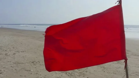 Close up of a bright red flag with beach and ocean in the background Stock Footage 146756096