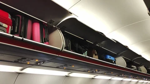 Close-up of bright suitcases lying on the shelves in the plane. Economy class Stock Footage 103867475
