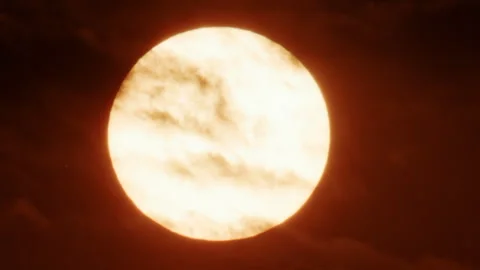 Close up of a bright sun partially covered by thick moving clouds, glowing in Stock Footage 336784441