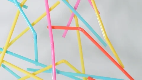 Close on brightly colored plastic single use bendable straws floating on surface Stock Footage 93960908