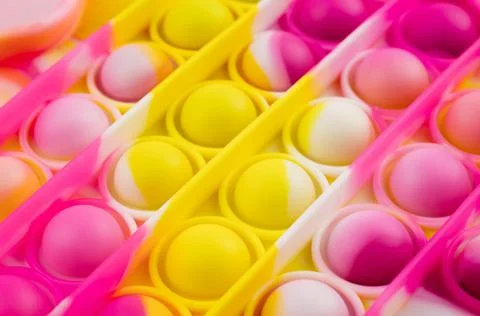 Close-up of a brightly colored Pop it fidget toy on a colored background Stock Photos