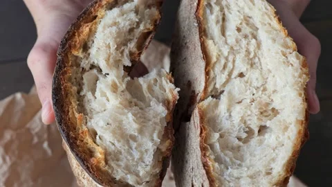 Close-up of broken bread with porous texture in woman's hands. Fresh baked bread Stock Footage 154784218