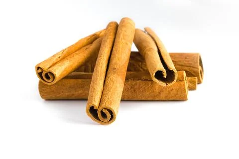 Close-up of broken cinnamon bark pieces on a white surface, emphasizing the.. Stock Photos