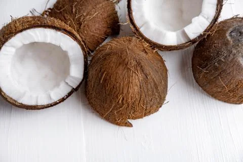 Close-up of a broken coconut fruit on a white wooden background with a place for Stock Photos