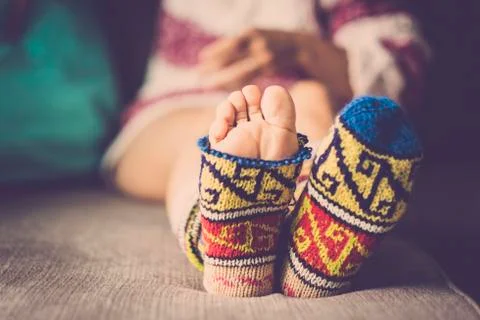 Close up of broken funny warm winter socks with feet outside - nice woman sit Foto stock