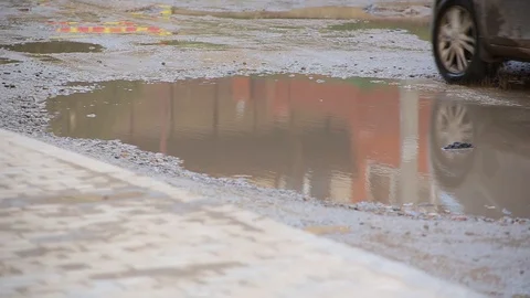 Close-up broken road with dirty puddles on which cars passing with difficulty Stock Footage 101540205