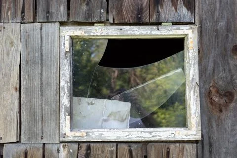 A close up of a broken window, showing its aged frame and shattered glass. 写真素材