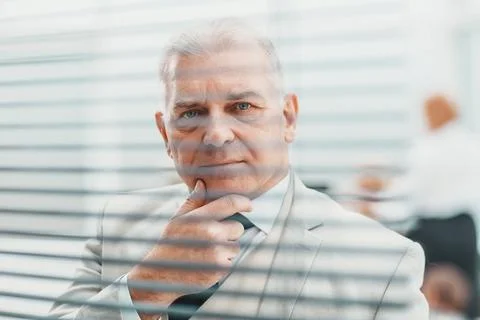 Close up. brooding elderly businessman standing in front of office window. Stock Photos