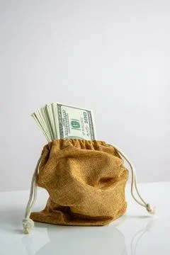 A close-up of a brown burlap sack with a drawstring top, filled with US dol.. Stock Photos