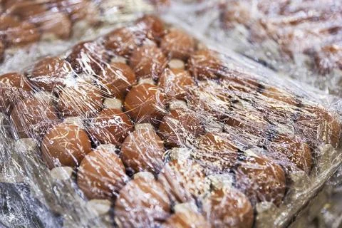 Close-up of Brown Chicken Eggs in Cardboard Tray Wrapped in Plastic Film Stock-Fotos