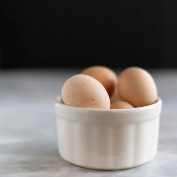 Close-up of brown eggs in ceramic white bowl. Stock Photos