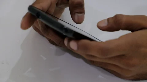 Close up of brown hands typing n a touch screen mobile phone smart device Stock Footage 100054935