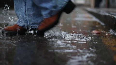 Close-up of brown heeled boots stepping through puddle in winter rain day, .. Stock Footage 292984234