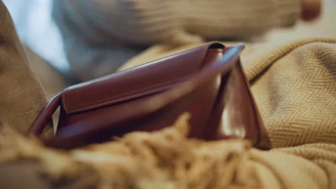 Close up of brown leather handbag resting on textured fabric with soft lighting Stock Footage 346734254