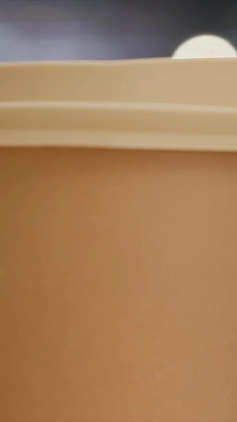 Close up brown liquid in cup with beige lid showing subtle movement against soft Stock Footage 344670094