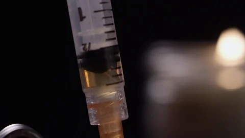 Close-up of brown liquid heroin getting sucked up into a syringe in a dark room Video stock 119100167