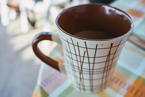 Close-up of a brown patterned ceramic coffee mug sitting on a colorful tabl.. Stock Photos
