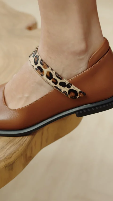 Close-up of brown shoe with leopard strap on wooden table Stock Footage 320896094
