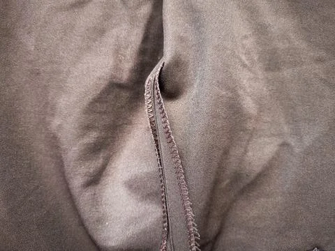 Close-up of brown smooth fabric texture with stitched overlock hem seam Stock Photos