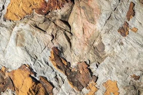 Close up of brown stone rock formation texture with black cracks throughout Stock Photos