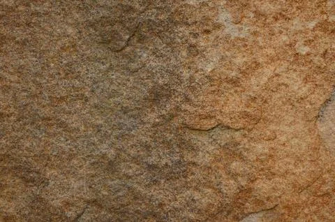 A close up of a brown stone wall with a rough texture. Stock Photos